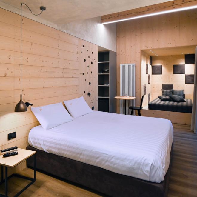 Modernes Zimmer mit Holzwänden und Doppelbett.
